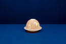 A white, unglazed chinese porcelain tealight candle holder with a dome cover, featuring a lithophane design that becomes visible when backlit.